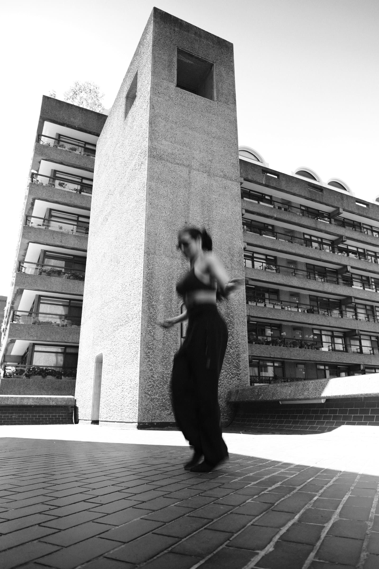 Walking past a Barbican tower, in black and white